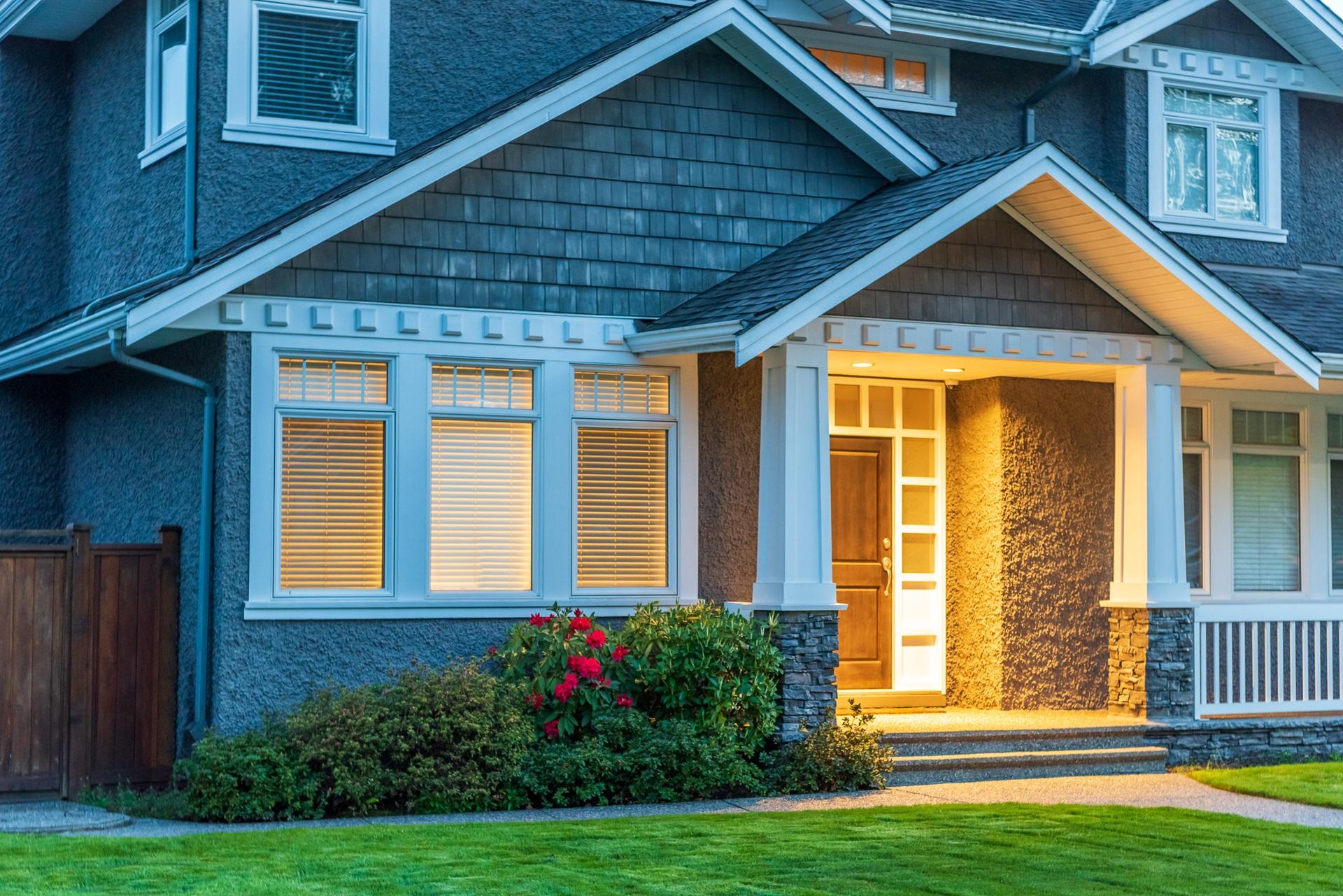 Hausfassade am Abend mit beleuchtetem Eingangsbereich und Fenstern | Mülltonnenbox